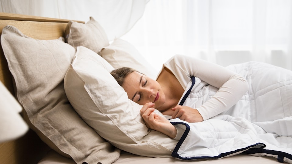Pessoa dormindo de lado em cama com roupa de cama clara